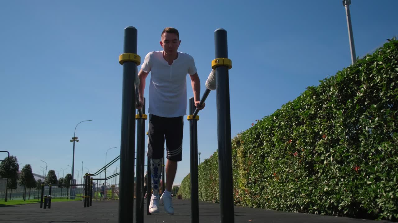 hombre con pierna protésica haciendo ejercicio en barras paralelas