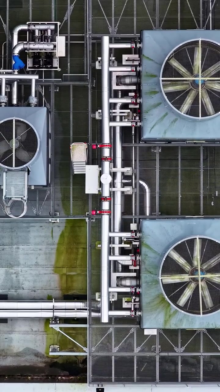Sistema industriale di condizionamento e ventilazione dell'aria con ventole rotanti sul tetto di un edificio in vista aerea verticale.