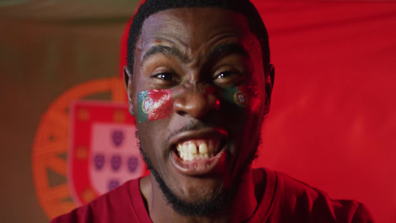 retrato de un feliz seguidor de fútbol afroamericano con la bandera de portugal sobre la iluminación rosa