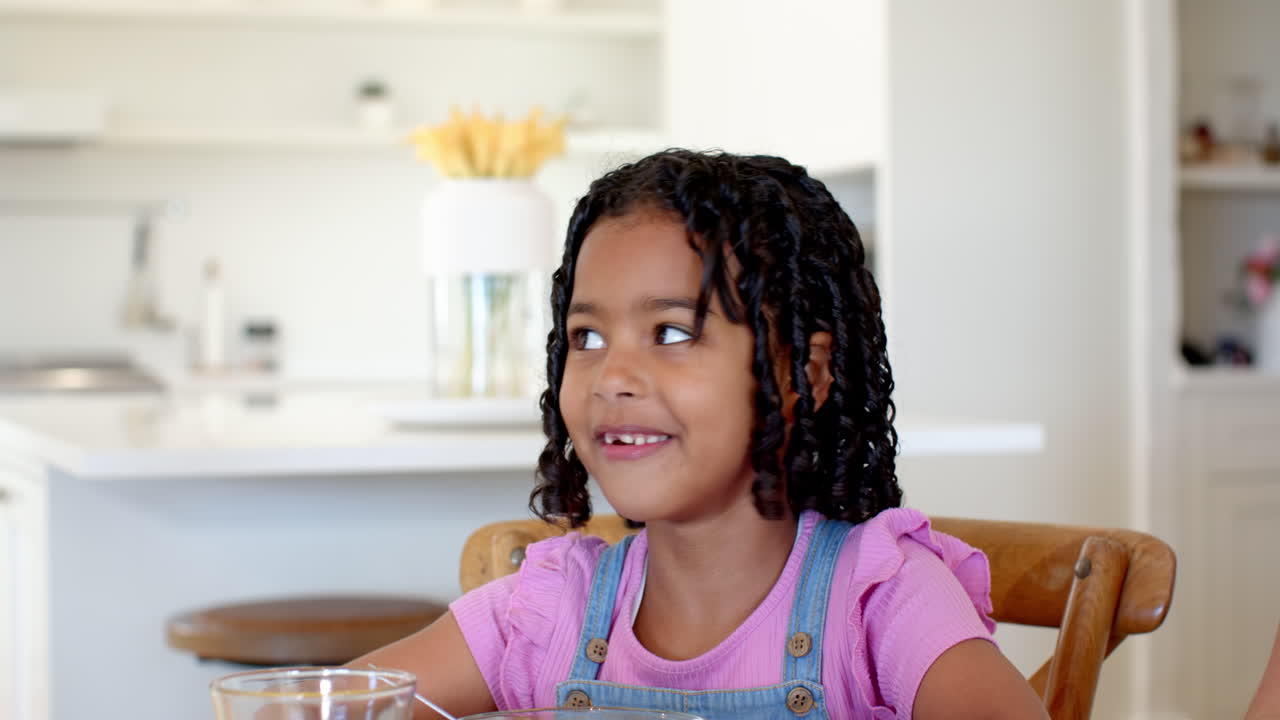 African American girl enjoying breakfast with orange juice and fruit at home