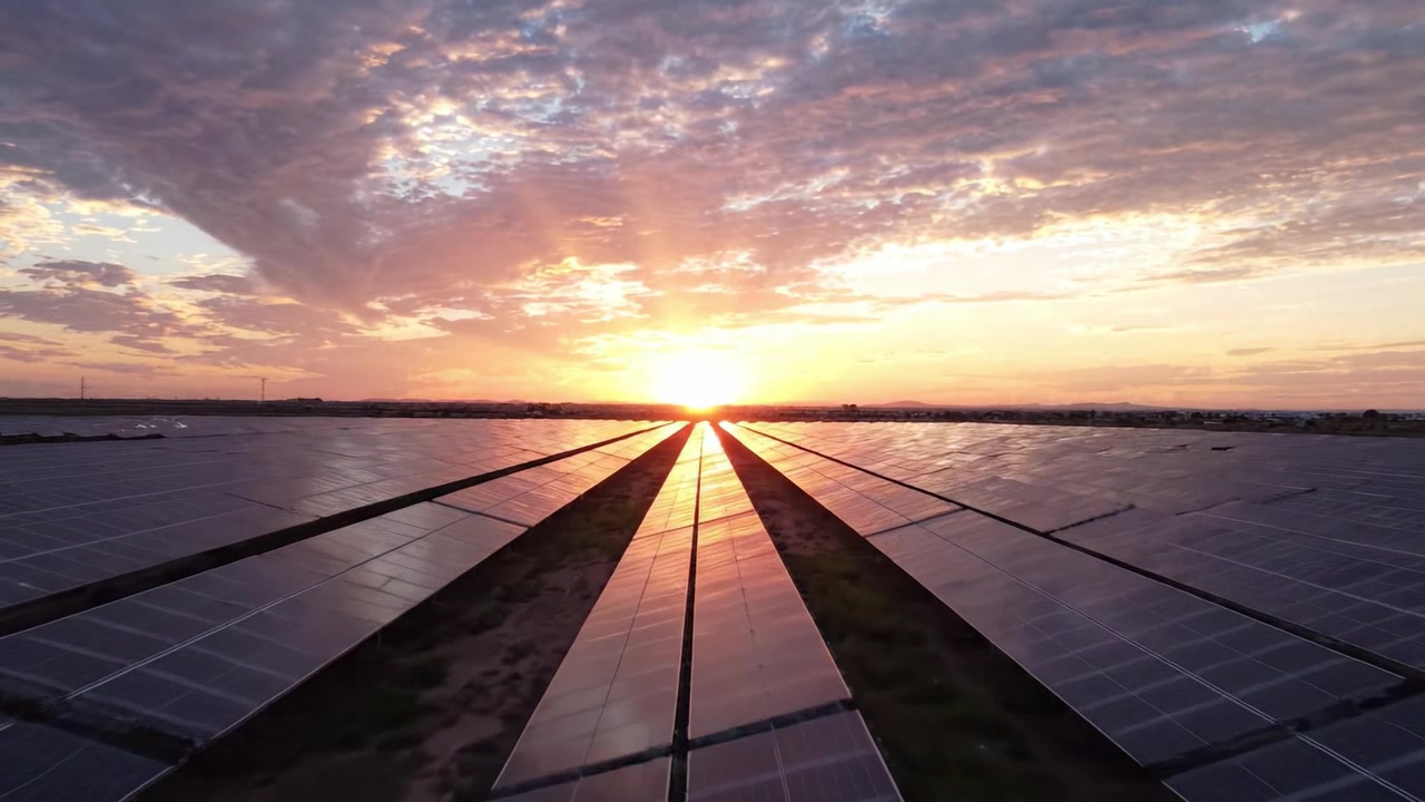 Betagende solopgang over en solcellepark, der viser rækker af fotovoltaiske paneler oplyst af gyldent lys