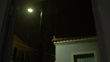 los relámpagos iluminan el cielo nocturno durante la tormenta con lluvias torrenciales alrededor de la vista de las farolas desde la ventana de mano