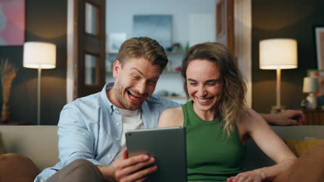 amantes riendo viendo comedia de tableta en casa de cerca. dos personas divirtiéndose