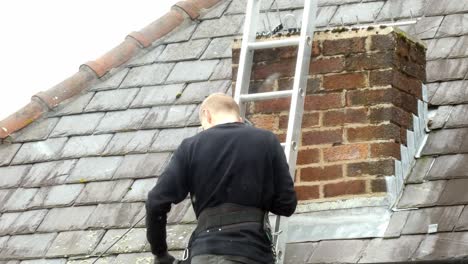 man on ladder installing television aerial on home chimney roof