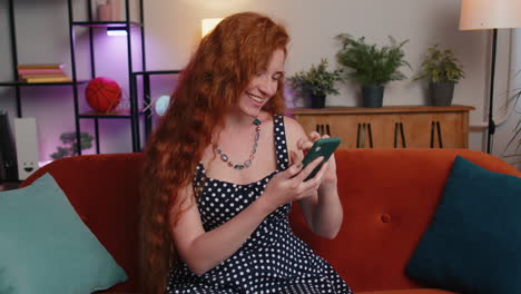 chica pelirroja en casa usar teléfono inteligente escribir navegación, wow sí descubrió gran gran victoria celebrar