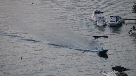 hombre en bote pequeño motorizado, viajando de regreso a tierra después de amarrar el barco