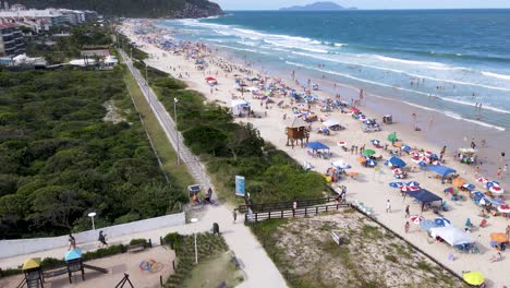 aerial view of tropical tourist beach with hotels and summer houses facing the sea with many people on the sand