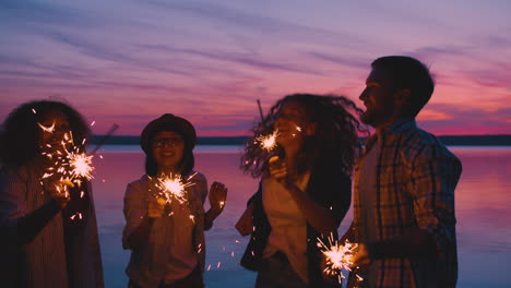 friends celebrating at sunset by the lake with sparkler