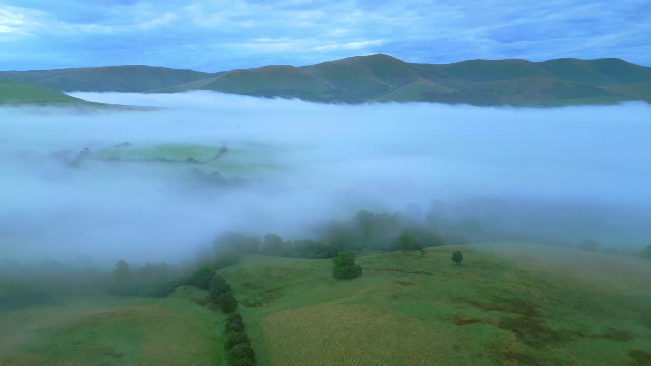 volando sobre el campo inglés hacia el banco de niebla y las montañas al amanecer