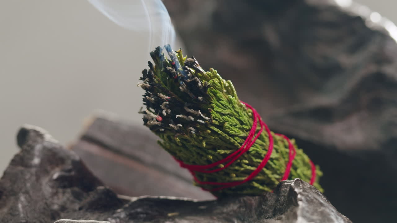 Person holding Palo Santo wood stick in hand, aromatic Palo Santo burning on black background, smoke spreading around, slow motion video clip, high quality 4k close up footage. High quality 4k footage