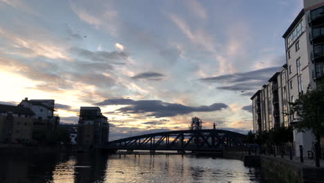 Disfrutando-De-La-Puesta-De-Sol-En-La-Orilla-Cerca-Del-Agua-De-Leith-En-Edimburgo,-Escocia