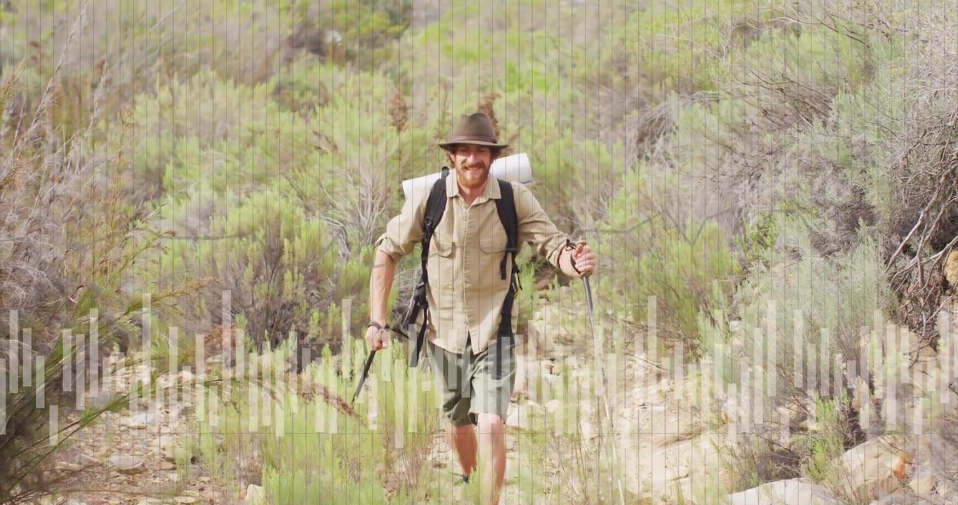 Hiker stepping onto hiking trail while scanning slope and planting poles negotiating uneven ground