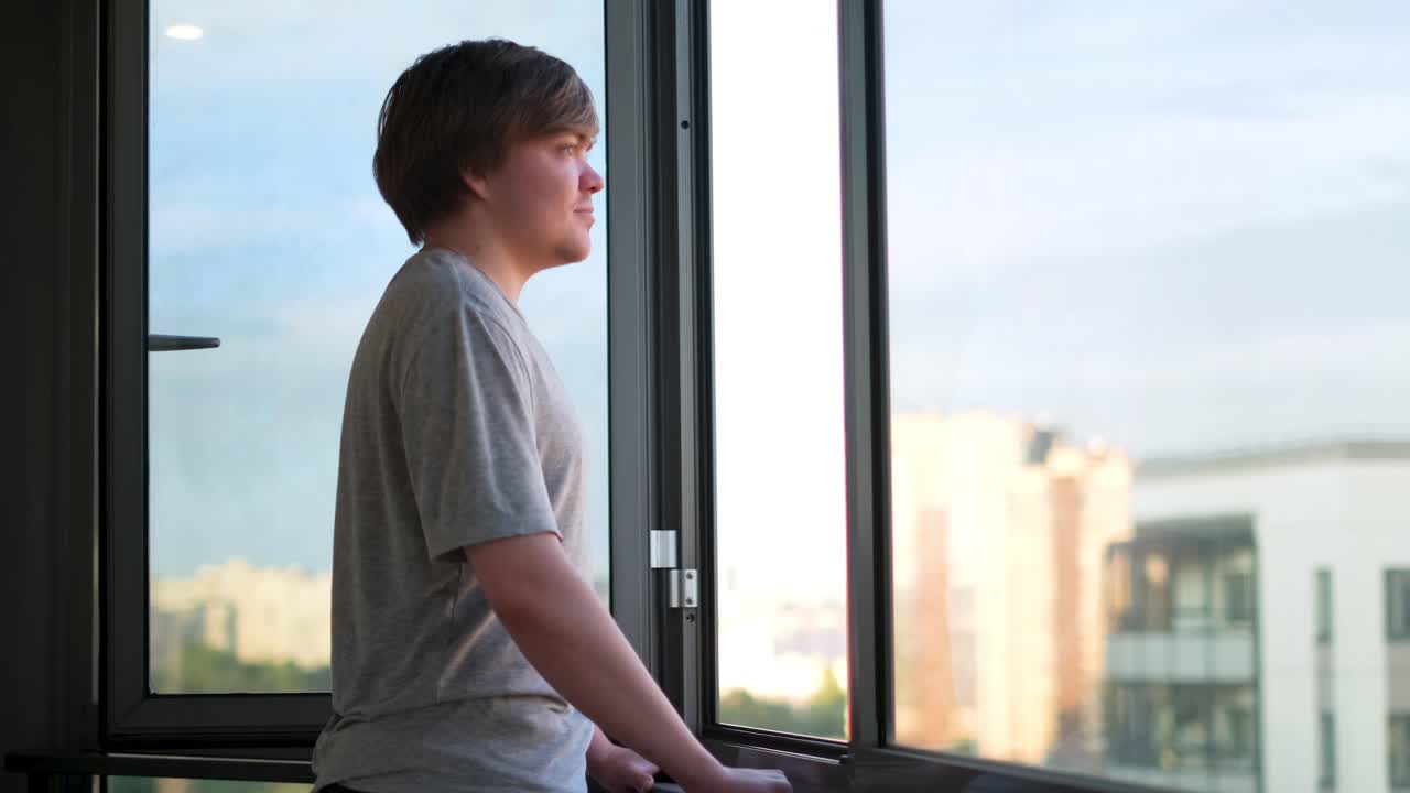 Young man looking out a window at city view