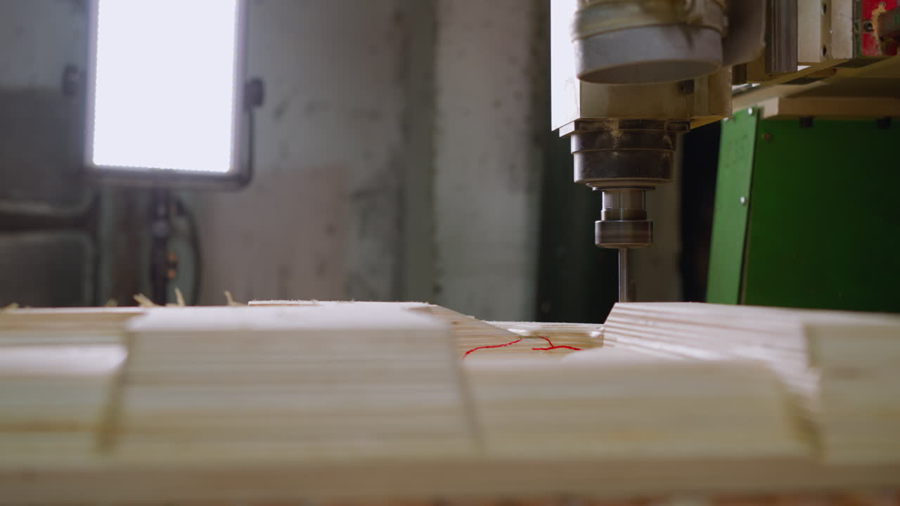 primer plano de una máquina cnc trabajando en madera contrachapada, resaltado por la iluminación del taller, la dispersión de aserradura
