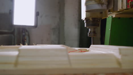 close-up of cnc machine at work on plywood, highlighted by workshop lighting, sawdust scattering