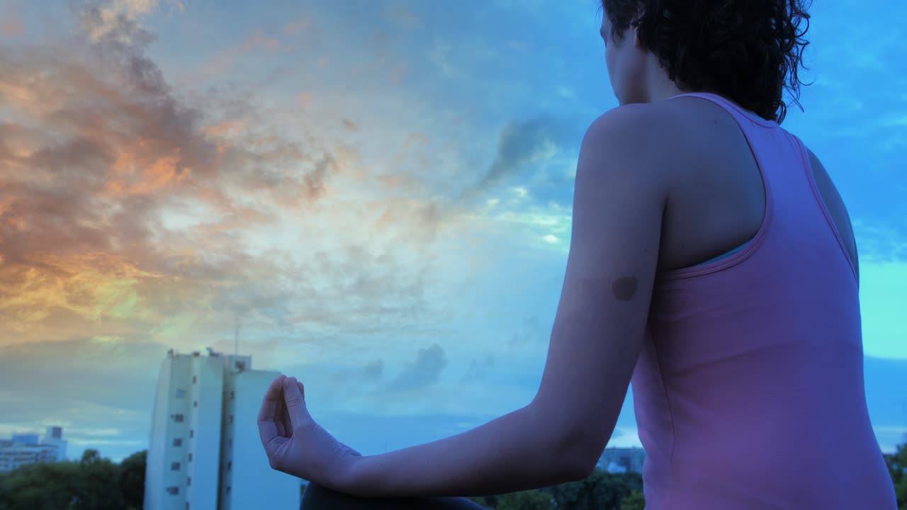 Donna che medita all'aperto con uno skyline sereno e un cielo al tramonto