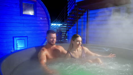 loving couple sitting and relaxing in the big hot tub. happy caucasian people in spa outdoors in winter.