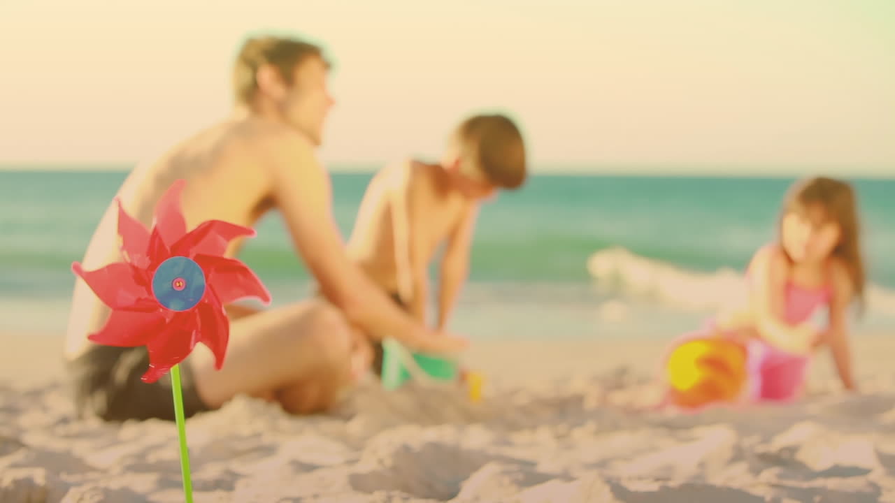 Animering av väderkvarn över leende vit familj lekande på stranden.
