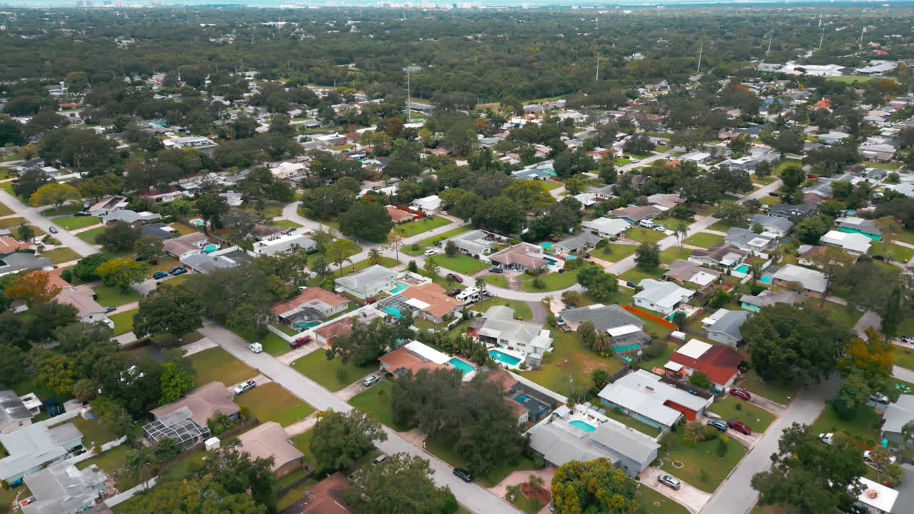 Aerial view over canal waters to a residential suburban neighborhood with intersecting streets and dense trees