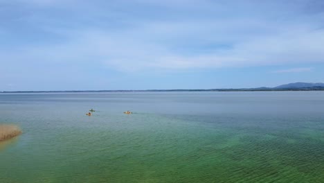 Szenischer-4-km-Flug-über-Einem-Kajakboot,-Das-An-Bayerns-Berühmtem-Chiemsee-In-Der-Ländlichen-Landschaft-Mit-Einem-Wunderschönen-Himmel,-Klarem-Blauem-Wasser-Und-Den-Alpenbergen-Im-Hintergrund-An-Einem-Sonnigen-Tag-Kajak-Fährt