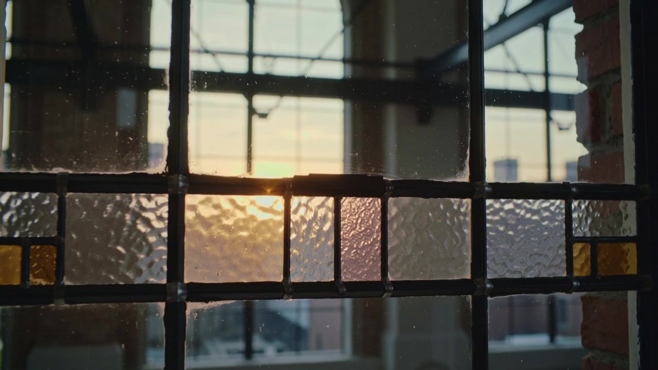 Moving sun casting glow across loft textured glass panel at sunset, with lead grid, amber tiles