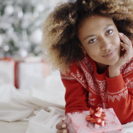 Nachdenkliche-Junge-Frau-Mit-Einem-Weihnachtsgeschenk