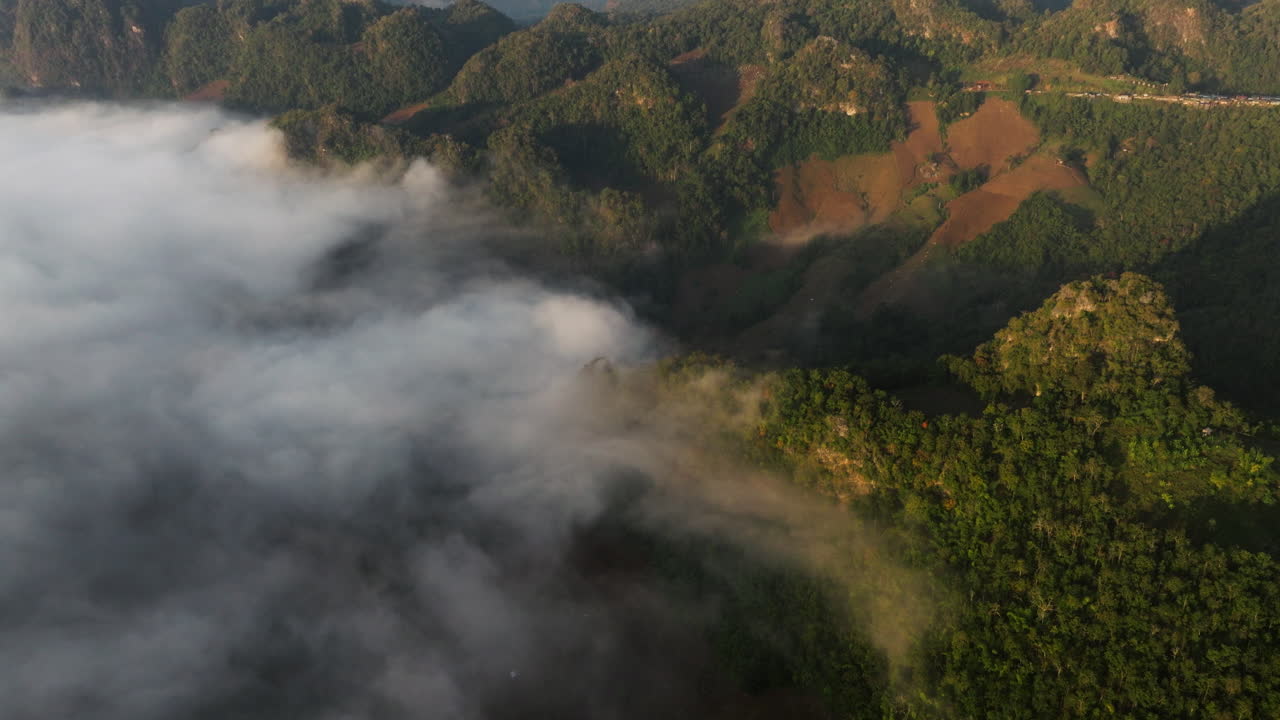 Mare di nebbia che copre un paesaggio montuoso vicino al villaggio di Ban Jabo in Thailandia all'alba. Inquadratura aerea dall'alto verso il basso