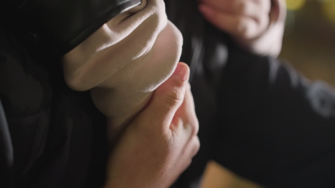 Close up romantic moment as man gently rubs partner's hand wrapped around his shoulder, expressing affection and connection in intimate gesture with soft bokeh lighting in urban nighttime background