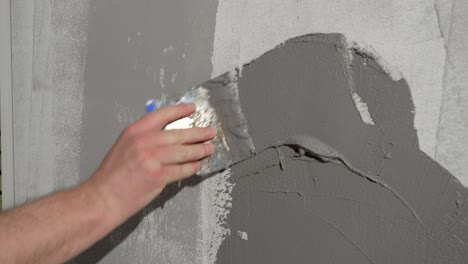 a man is applying decorative plaster to the wall