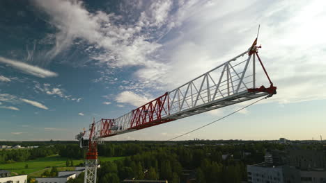 Flat-top-tower-construction-crane's-working-jib,-sky-and-forest-in-the-background