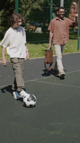 A man and children playing soccer and sharing hugs on an outdoor court