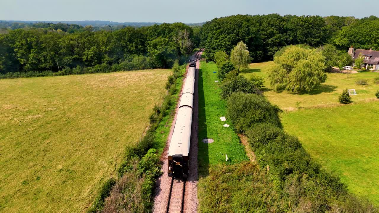 놀라운 공중 드론 영상은 옛 증기 열차가 그림 같은 시골을 가로질러 날아가며 경치 좋은 풍경을 통해 여행을 포착하는 동안 뒤에서 따라갑니다.