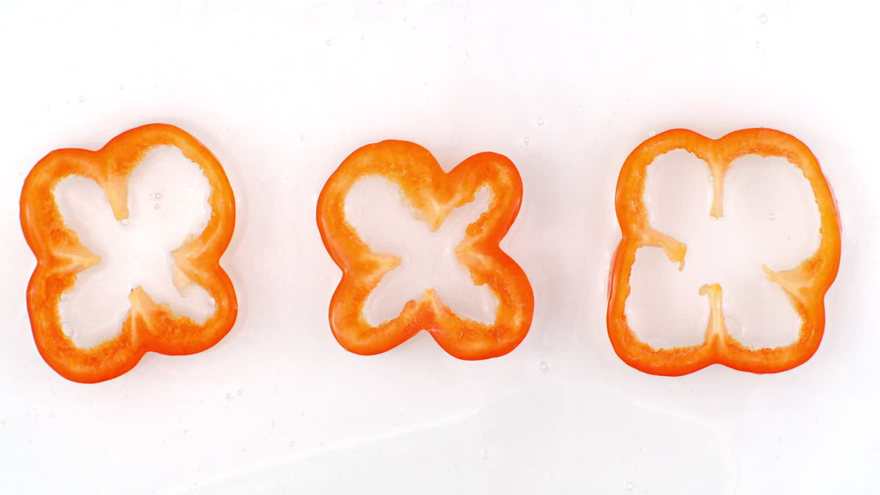 세 개의 은 고추가 백색의 배경에 서서히 떨어지는 물 어리에 누워 있습니다.