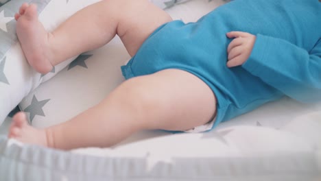 little child sucks dummy bothering legs in crib with chiffon