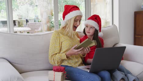 madre e hija abriendo cajas de regalos mientras tienen un video chat en la computadora portátil en casa