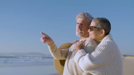 romantic senior couple hugging while talking and enjoying the view on the beach