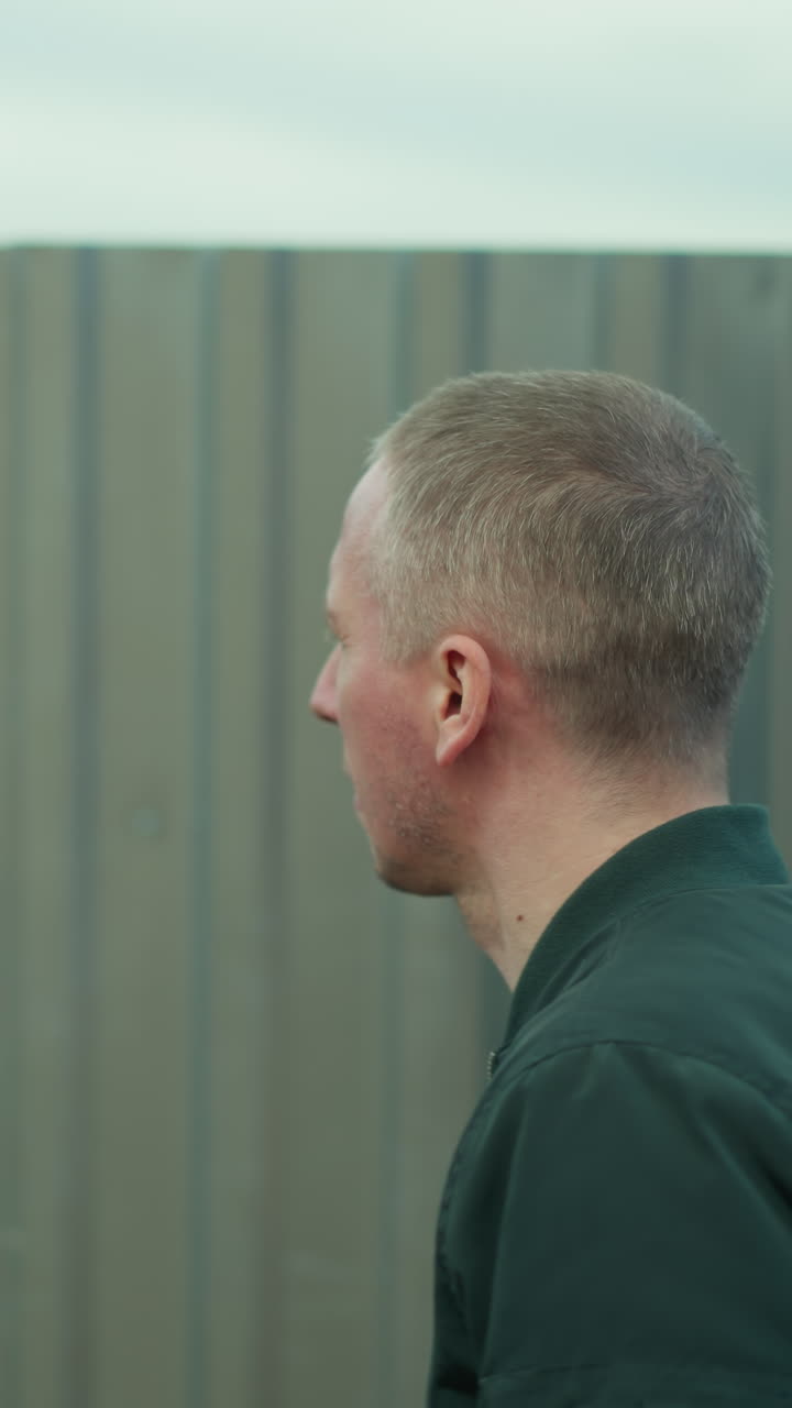 초록색 재을 입은 남자가  울타리를 따라 걸어서 주변을 둘러보고 있는 모습