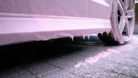 side skirt of a black car with dripping pink snow foam