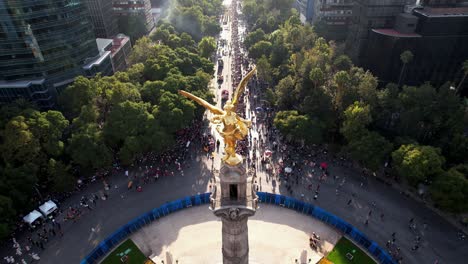 aerial view of el ángel de la independencia in mexico city with a large crowd gathered on reforma avenue