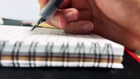 una mano que escribe con pluma en un cuaderno