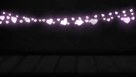 Animation-of-purple-heart-shaped-glowing-fairy-lights-hanging-against-copy-space-on-black-background