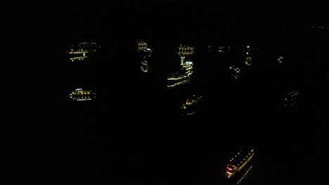 Aerial-night-view-of-Ha-Long-Bay-Vietnam-famous-travel-destinations,-cruise-luxury-yacht-boat-illuminated-moored-on-open-water