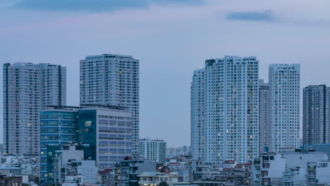 Day-to-night-time-lapse-in-densely-populated-urban-area-with-artificial-electric-lights-coming-on-in-illuminated-buildings