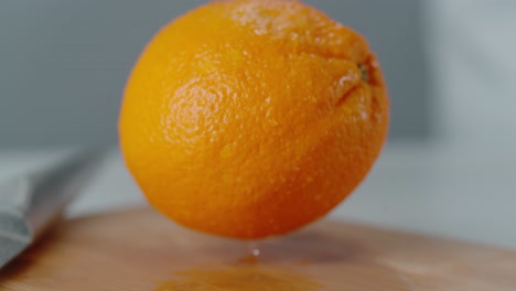 orange landing on cutting board with water droplets bouncing