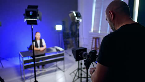 rear view of a male standing in front of camera. female blogger making video for her blog.