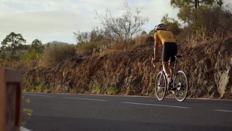 in slow motion, a biking athlete gracefully navigates along a mountain serpentine, observing a scenic island view, embodying the essence of a healthy lifestyle