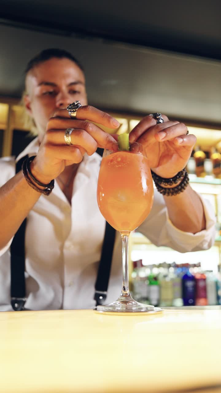 Barman garneert een verfrissende oranje cocktail met een groen schijfje
