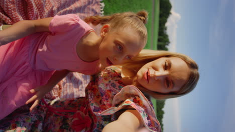 joyful woman and girl posing in city park. cheerful family speaking at meadow.