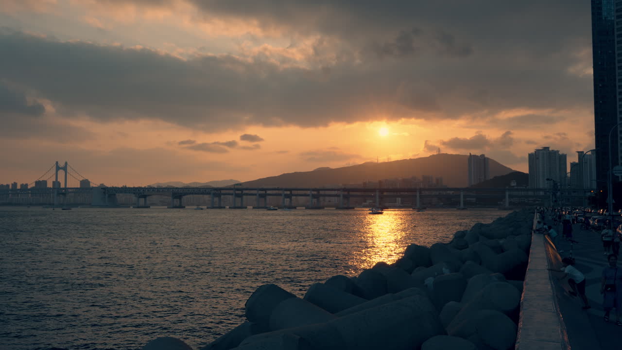 Tourists Admire Golden Sunset at Busan Marina Bay with a View of Gwangan Bridge or Gwangandaegyo