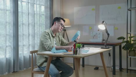 손에 있는 직물을 바라보는 레이아웃 을 가진 아시아인 디자이너